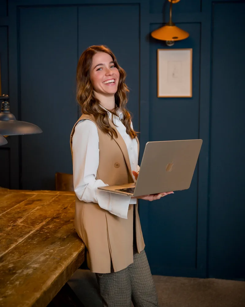 Kira Khoroshilova, founder of Diary of an SEO, smiling and holding a laptop
